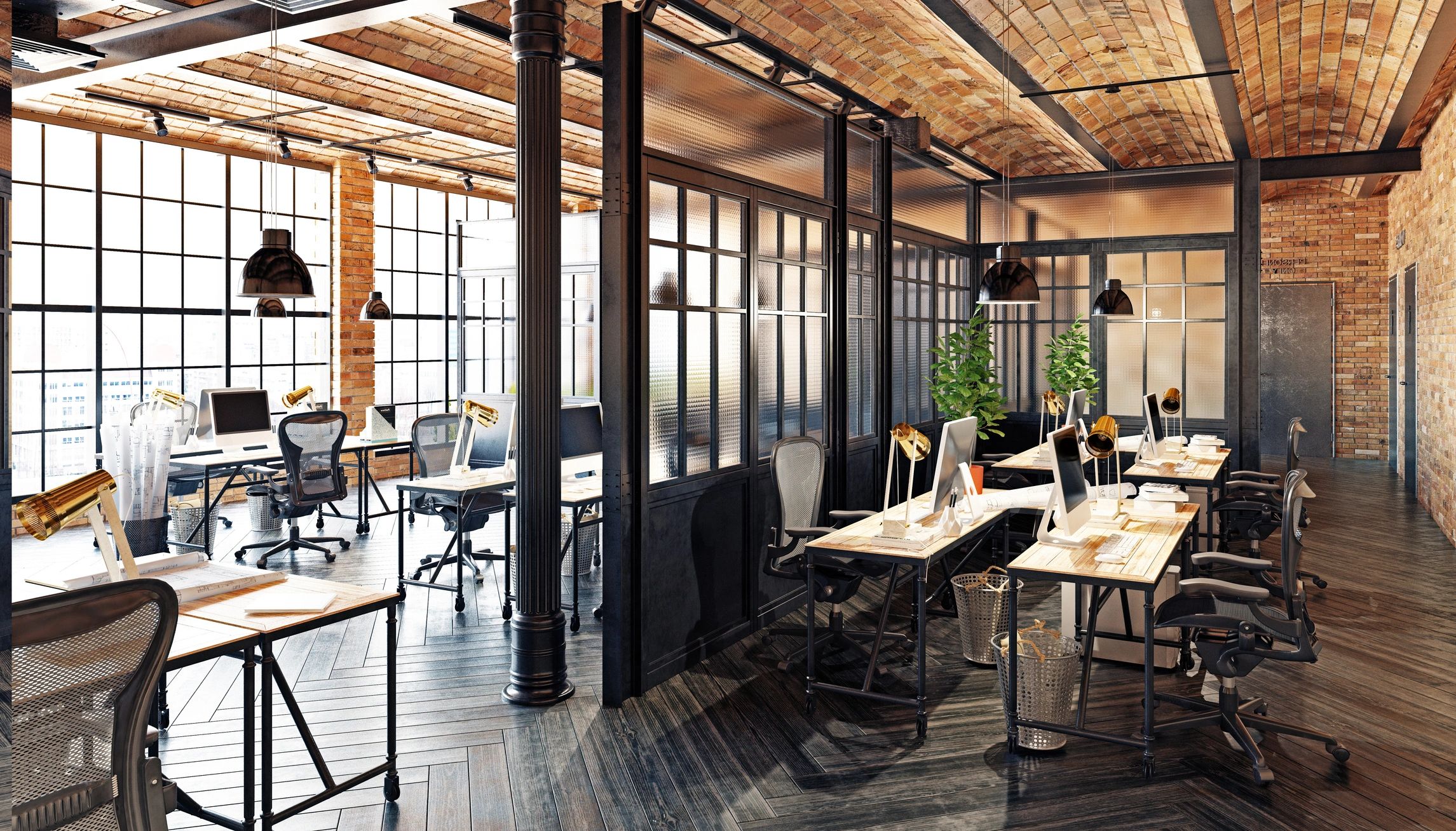 Open-plan office workspace with desks and brick walls